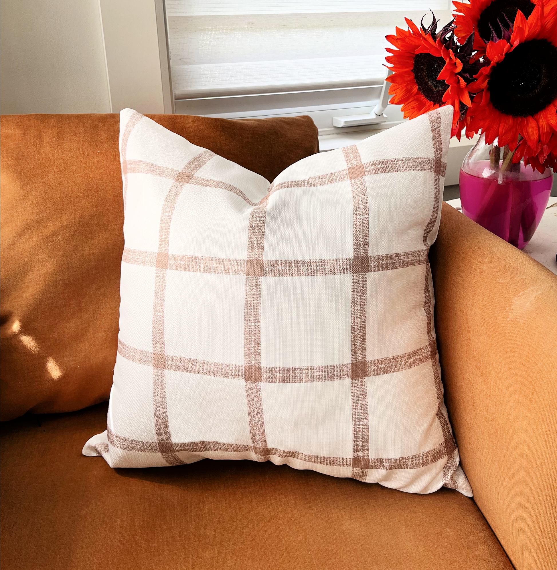 accent pillow with brown checkered battern on orange accent chair and red sunflowers