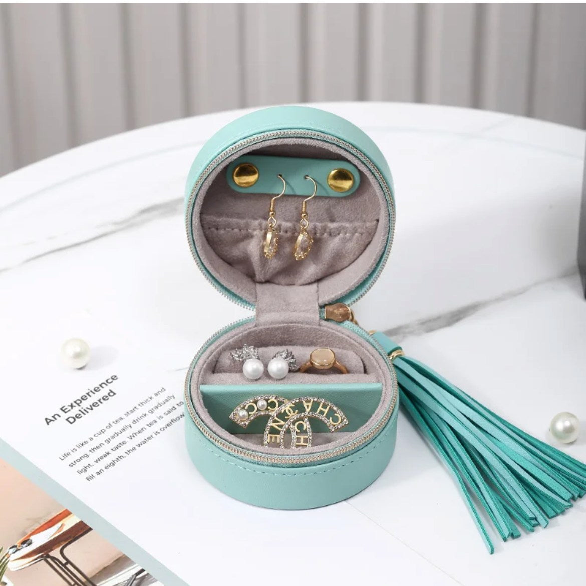 open round seafoam jewellery case with gold zipper matching hassle holding earrings