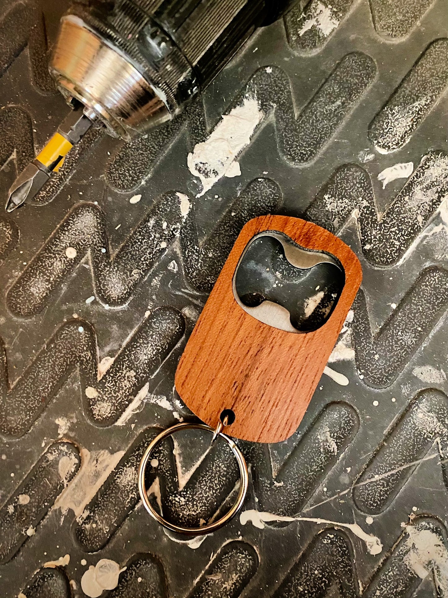 wood keychain bottle opener on work bench beside drill