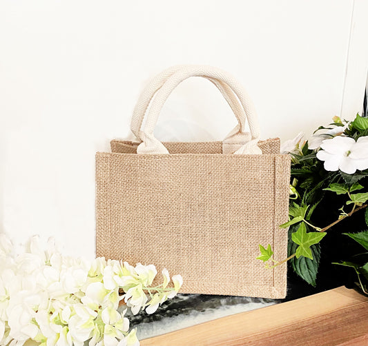 jute gift bag with material handle with white flowers on white background 