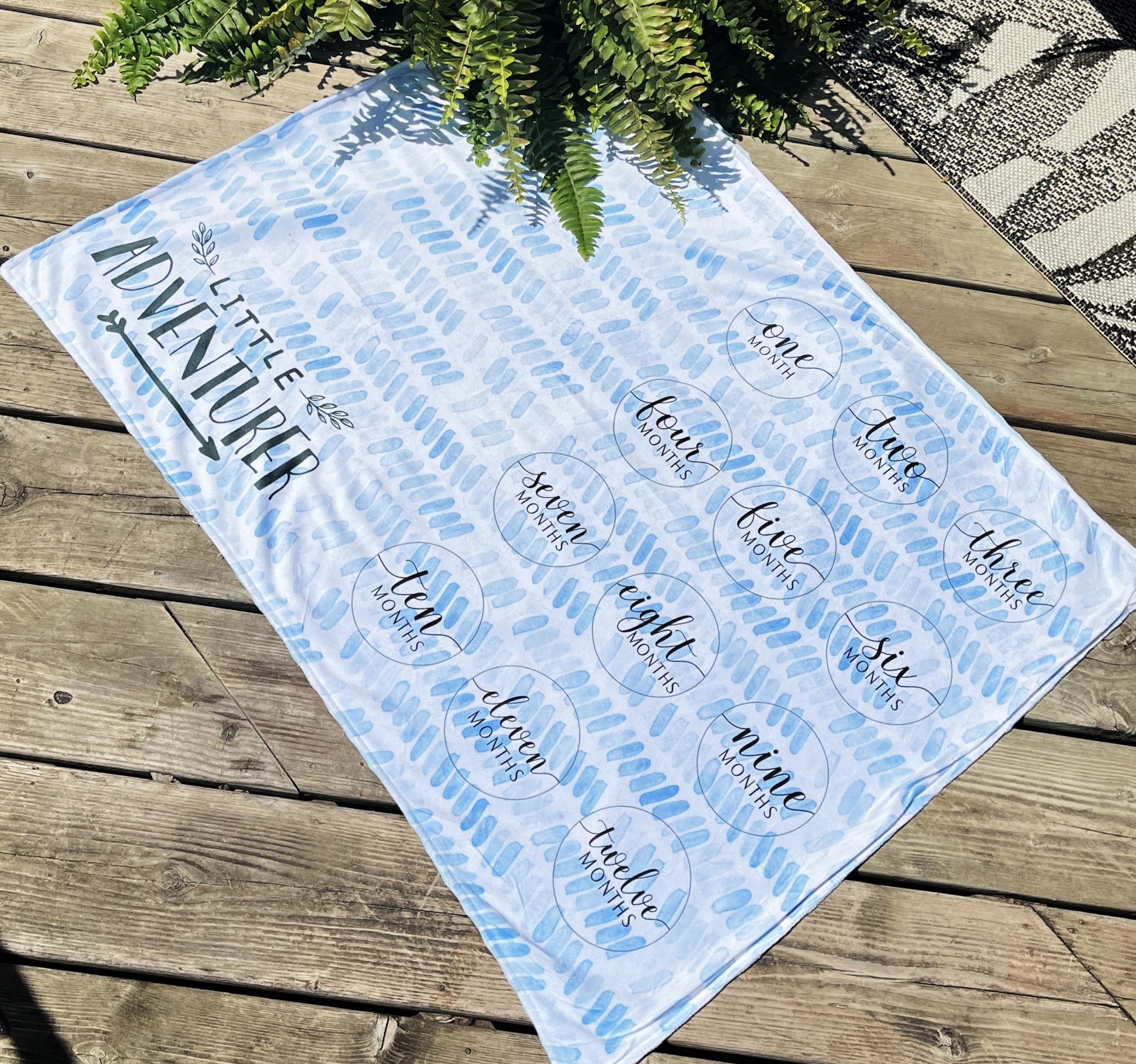 personalized milestone baby blue minky blanket little adventurer on wood background with fern