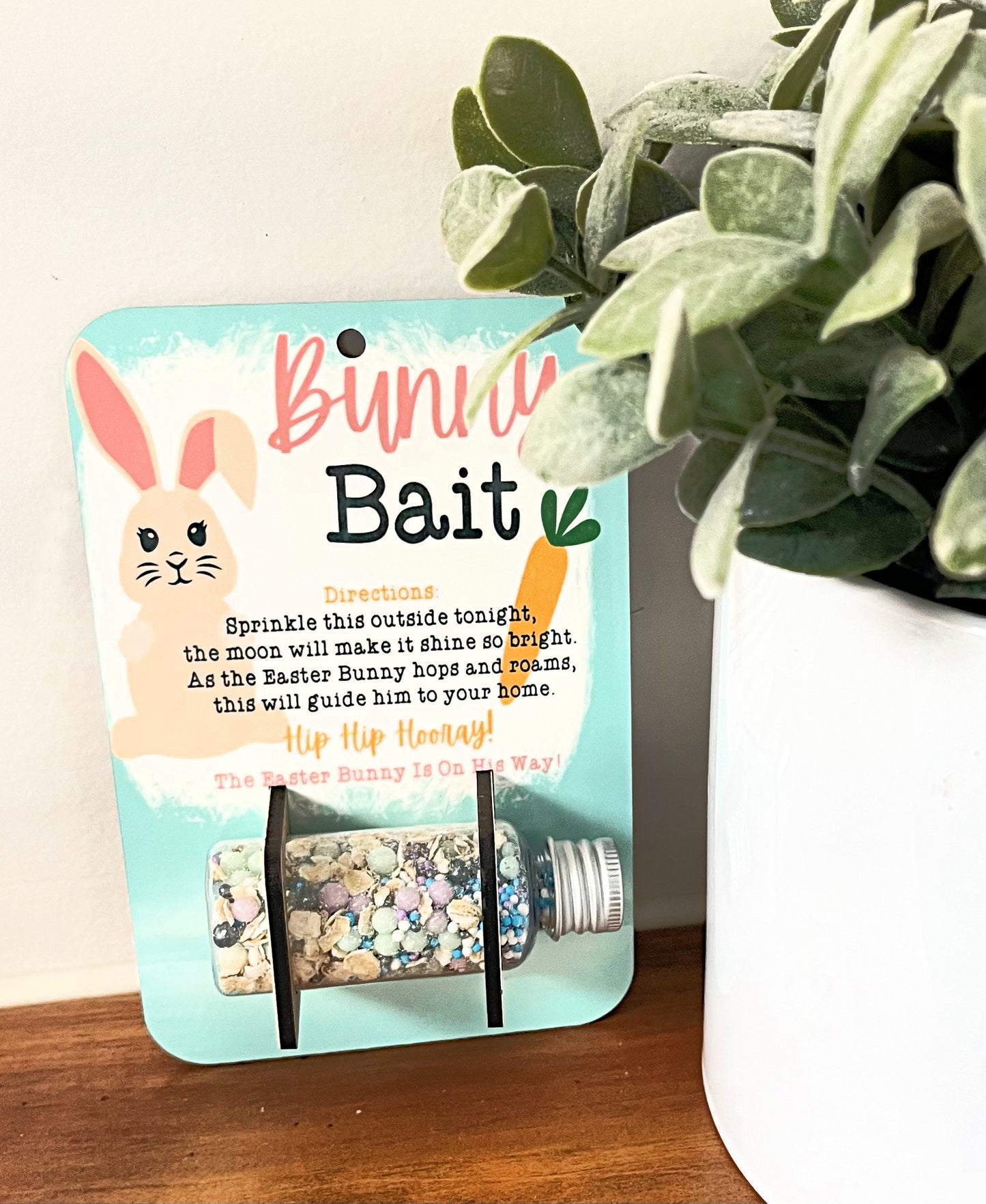 bunny bait food holder with sprinkles and oatmeal in bottle on wood desk by plant