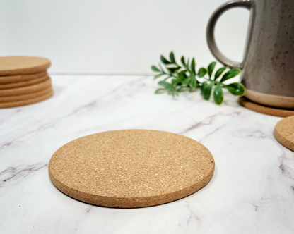 circle cork coaster on marble top with clay mug in the background and green sprig