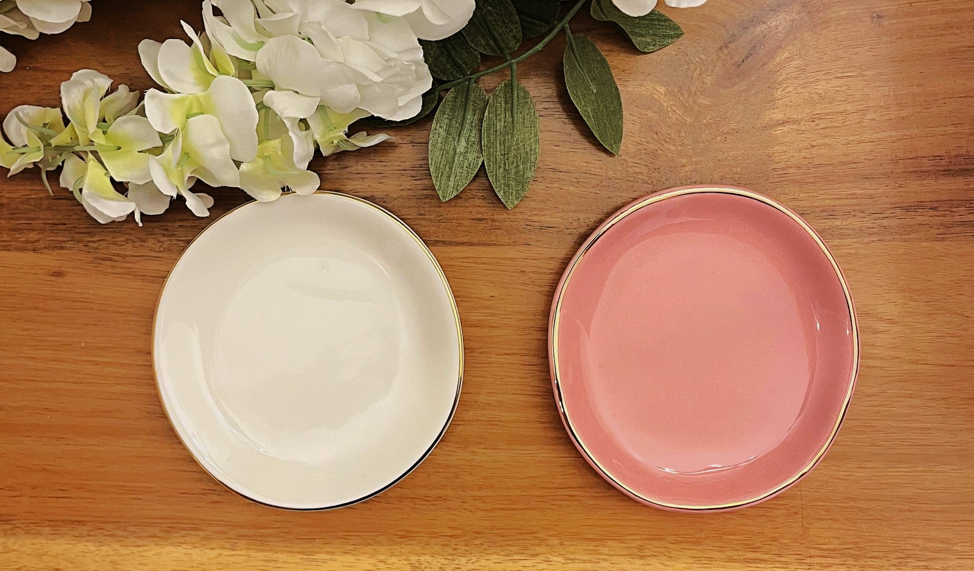 white and pink gold rimmed ring dishes on wood background with white flowers