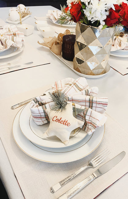 white velvet personalized star on Christmas table setting with plaid napkins and flowers in gold vase