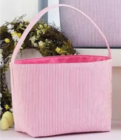 pink striped seer sucker Easter basket with handle on white stand with wreath and purple basket in background 