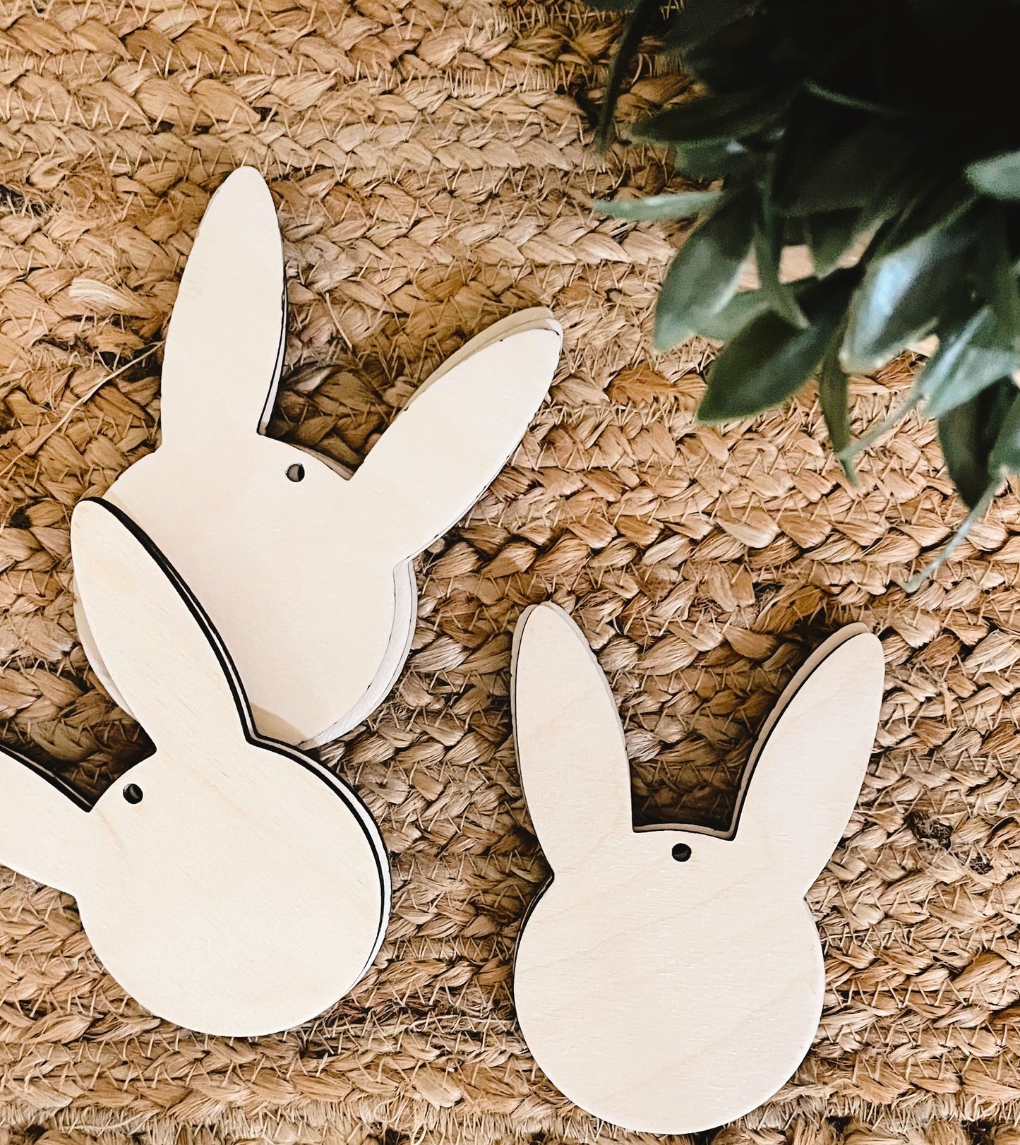 wooden bunny tags with pre drilled hole on woven background with green leaves