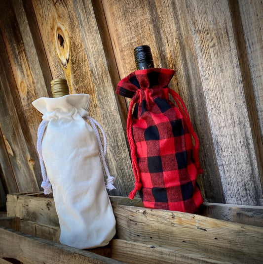 white and buffalo plaid wine bags with pull string over wine bottles on wood background