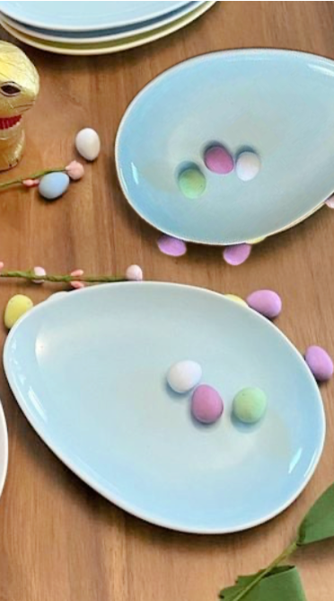 blue ceramic egg dished with candy coloured eggs on top with wood background