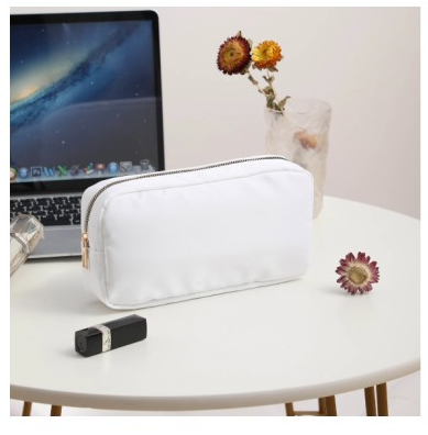 white makeup pouch with gold zipper on white table and laptop and make up