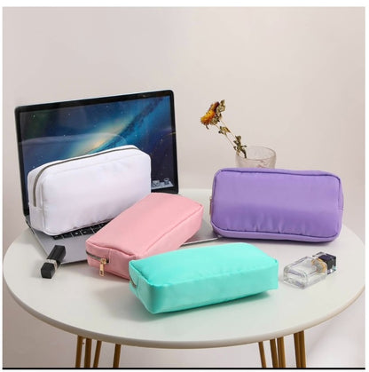 make up ouches with gold zippers on desk with laptop white background ,white pink mint and purple