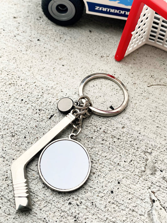 sublimation piece on hockey stick and puck key chain on concrete surface by net and zamboni