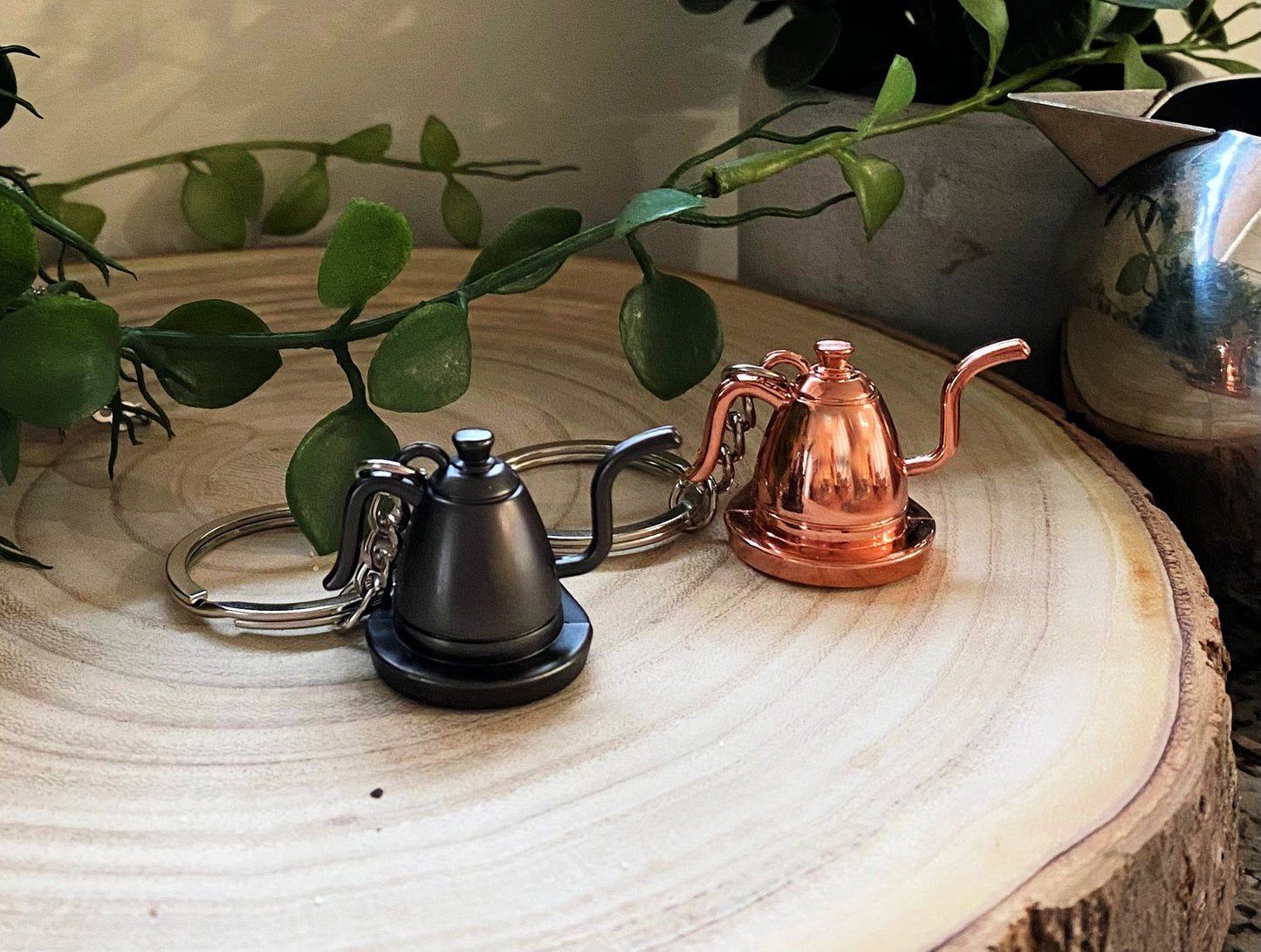 black and rose gold vintage tea pot key chains on wood slab by silver tea pot