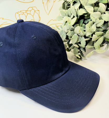 navy dad style women's baseball hat on white table by greenery