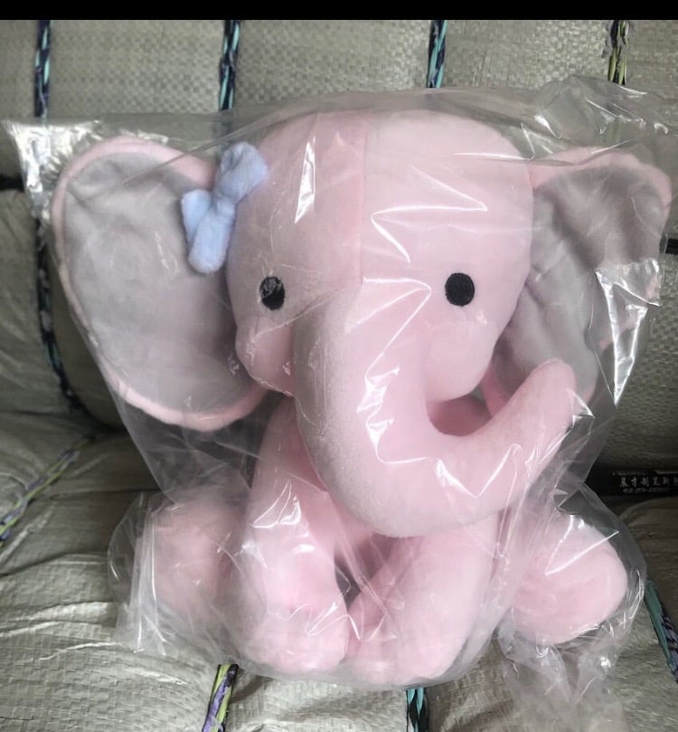 plush pink elephant with blue bow in clear packaging for birth stat