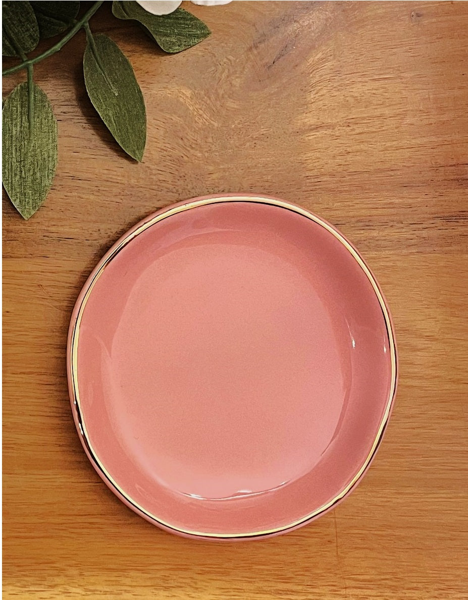 pink gold  rimmed ring dish on wood background with leaves